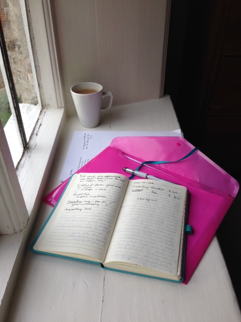an open notebook on a windowsill, a coffee cup in the near distance