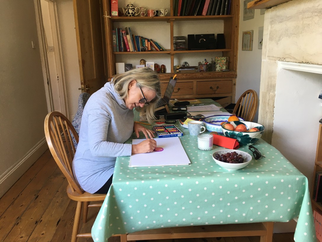 The image is of a white woman sitting at a table writing