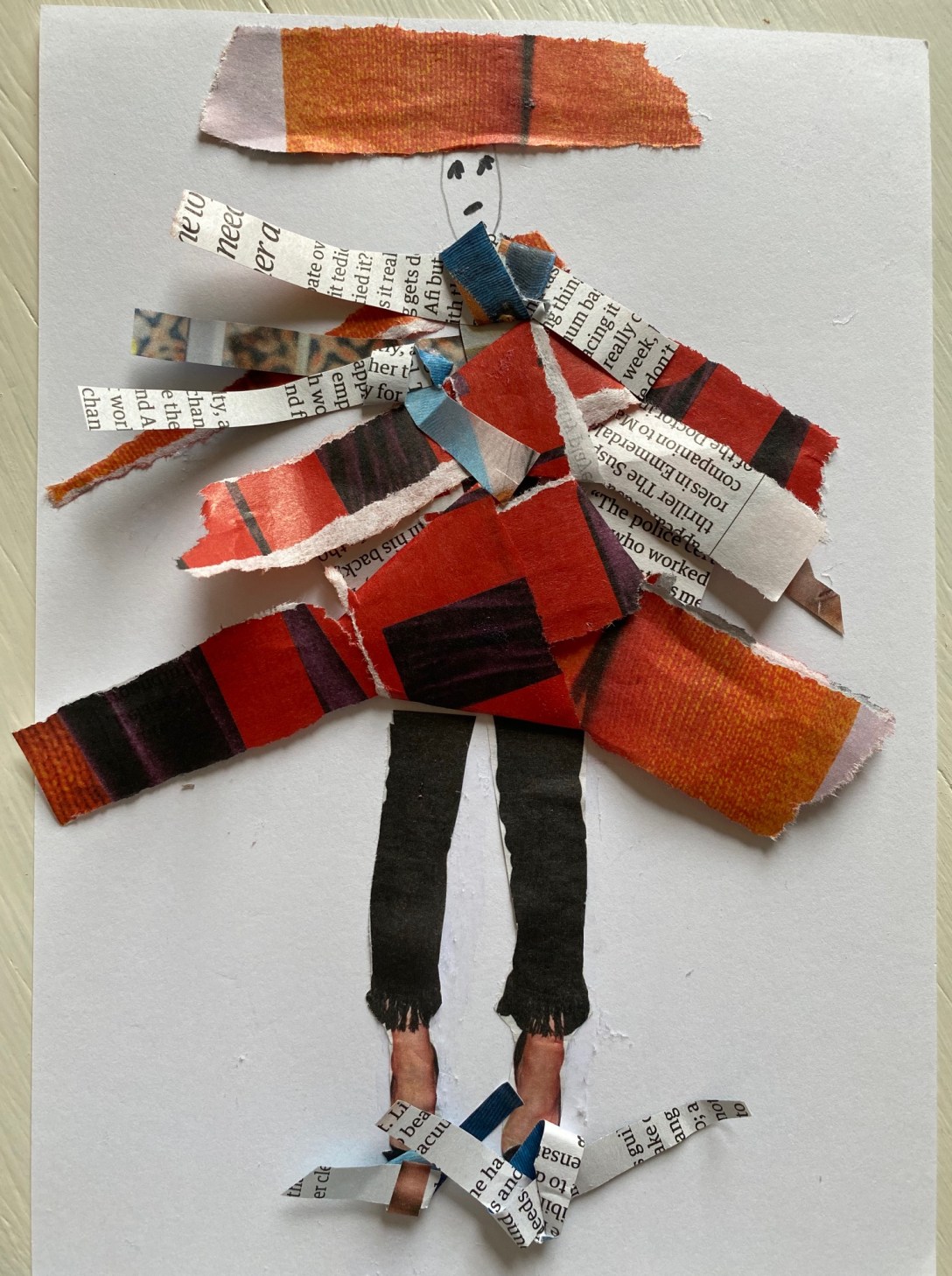 Pieces of magazine paper variously tied in loose knots and pasted onto plain paper as if clothing. A simple face hand drawn on the page and a pair of legs beneath.