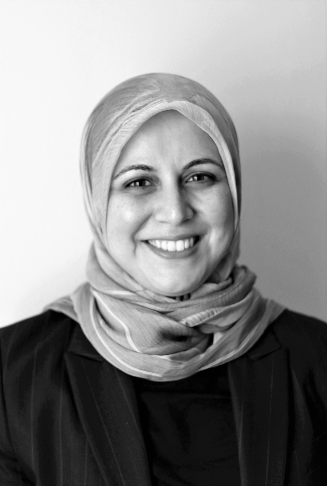 Abeer Ameer wears a hijab over her hair, she is facing forward and smiling